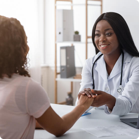 Profissional de saúde segurando a mão de paciente em consultório médico.